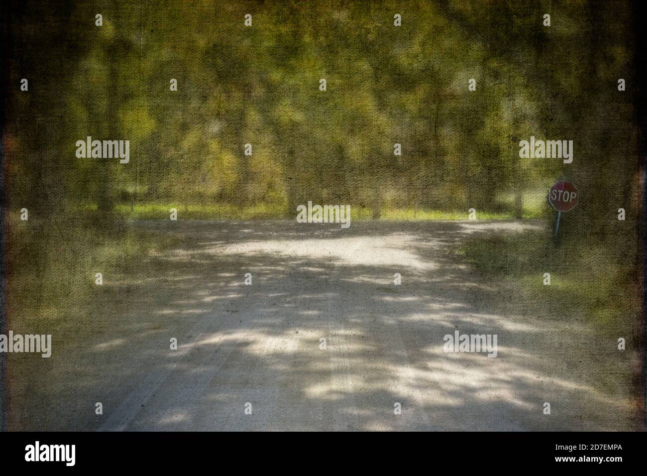 Texas unbefestigte Landstraße nähert sich einer Kreuzung mit rotem Stoppschild auf der rechten Seite. Haze ist in der Ferne und an den Seiten prominent. Stockfoto