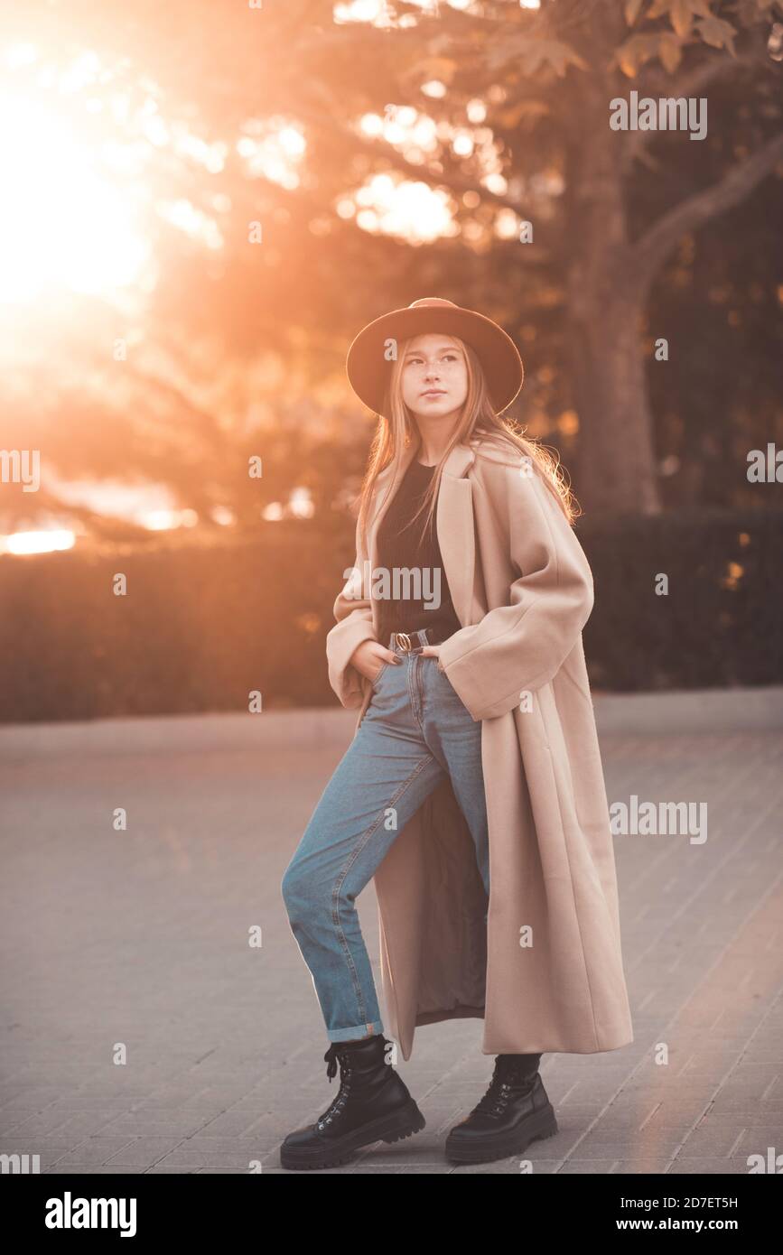 Blonde Teenager-Mädchen 13-14 Jahre alt trägt stilvolle Mantel und Hut zu Fuß in der Stadt Straße über Herbst Natur Hintergrund Nahaufnahme. Herbstsaison. Teenagerhood. Stockfoto