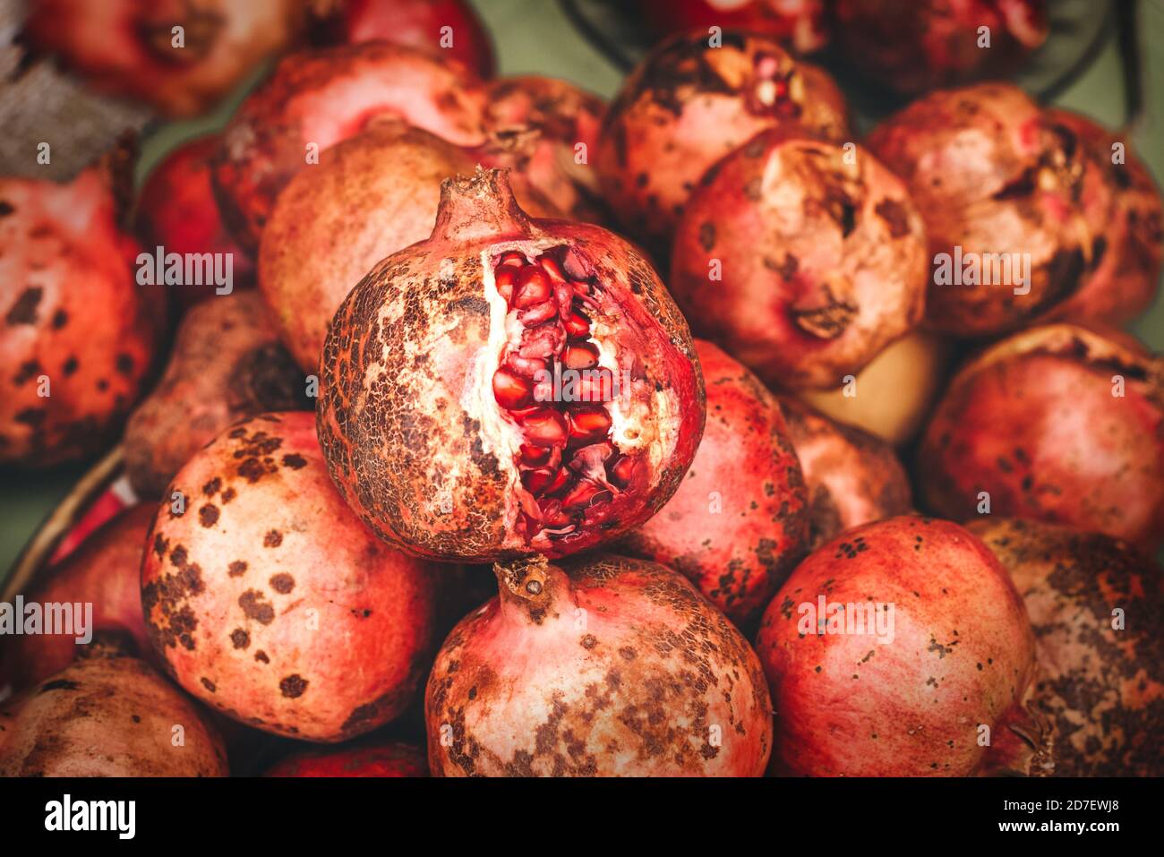 Reife Granatapfelfrüchte im Marktregal, überreifer Granatapfel liegt oben Stockfoto