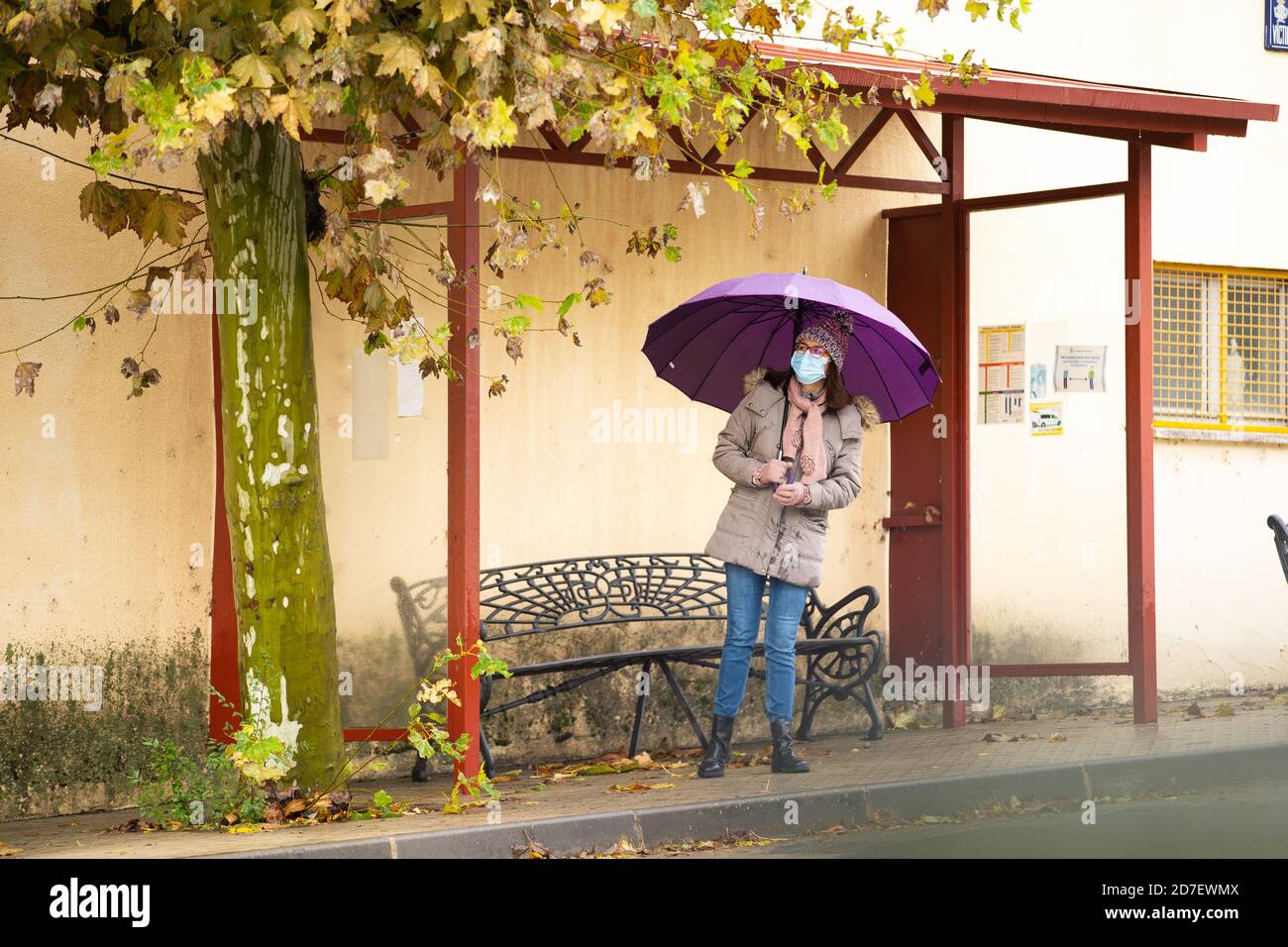 Frau mit Schirm an der Bushaltestelle Stockfoto