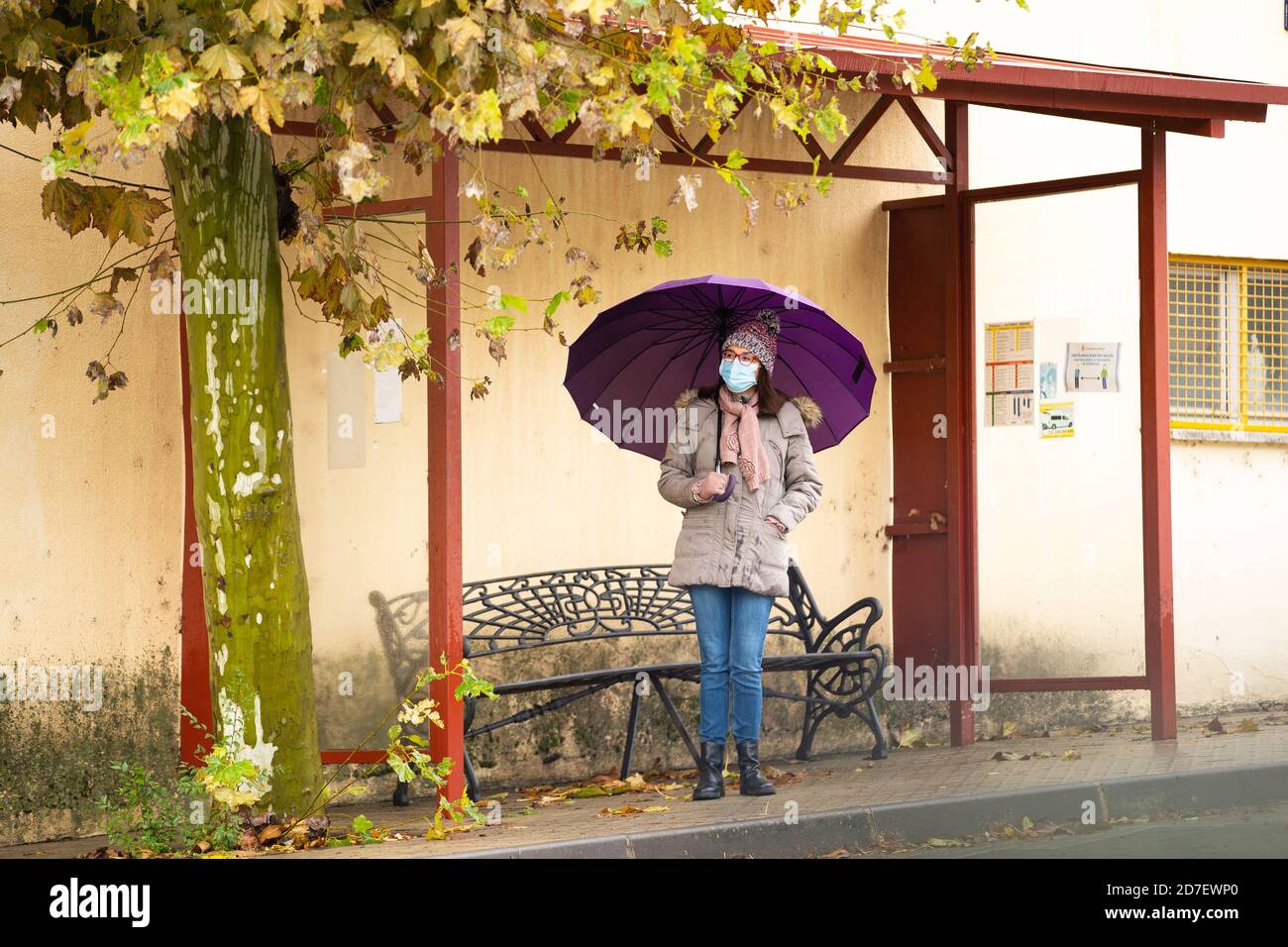 Frau mit Schirm an der Bushaltestelle Stockfoto