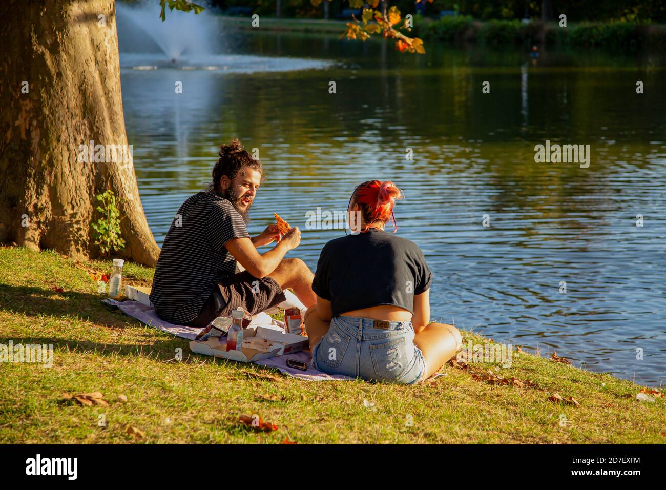 Frederick, MD, USA 10/14/2020: Ein hispanischer Pärchen sitzt an einem sonnigen Nachmittag auf einer Picknickdecke im Baker Park am Culler Lake. Sie essen Pizza und Stockfoto