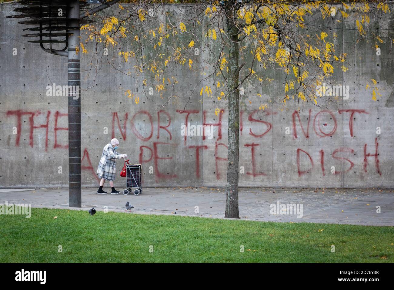 Manchester, Großbritannien. Oktober 2020. Ein Mitglied der Öffentlichkeit geht an Graffiti vorbei, das an einer Wand gesprüht wird und die wachsende Sorge um die Auswirkungen lokaler Sperren hervorhebt. Heute ist der letzte Handelstag für einige lokale Unternehmen, da eine Tier-3-Sperre für die Stadt und die umliegende Region durchgesetzt wurde, um zu versuchen, die Ausbreitung von COVID-19 zu verlangsamen. Kredit: Andy Barton/Alamy Live Nachrichten Stockfoto