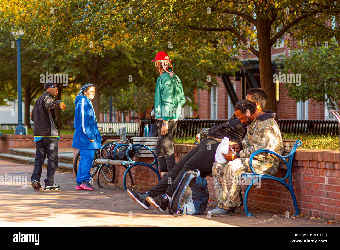 Frederick, MD, USA 10/14/2020: Mehrere Obdachlose streiten sich auf der Straße. Ein schwarzer Mann versucht, einem großen blonden Kaukasier etwas zu erklären Stockfoto