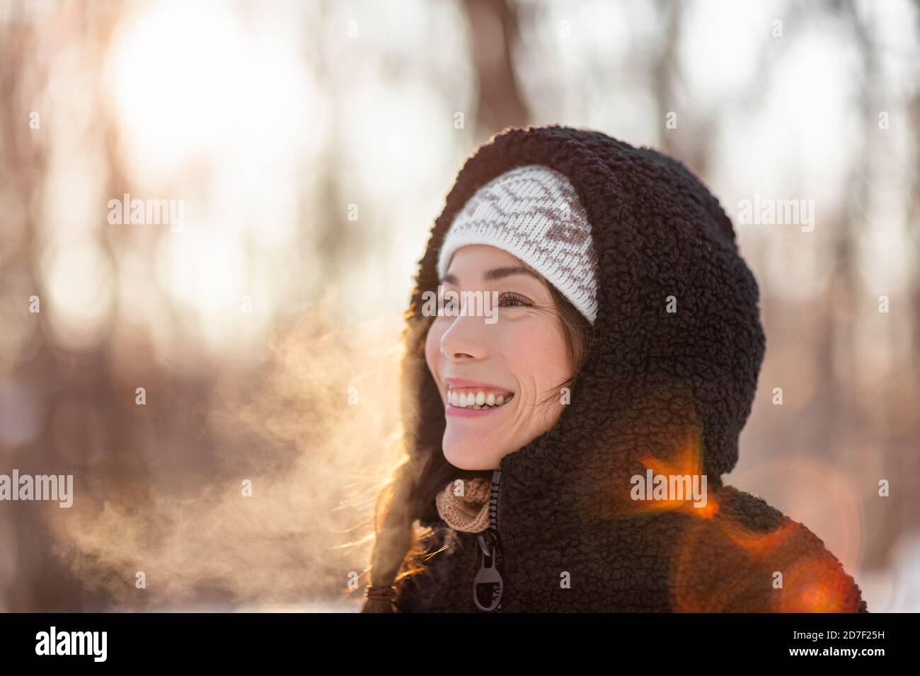 Winter kalt asiatische Frau atmen in der kalten Luft mit tau Nebel Wolken gegen Sonnenlicht im Wald Natur Spaziergang Outdoor-Lifestyle. Happy People Lifestyle Stockfoto
