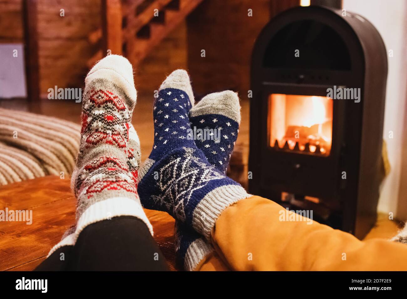 Füße in Wollsocken wärmend in der Nähe von Kamin im rustikalen Häuschen. Gemütlicher Winter. Stockfoto