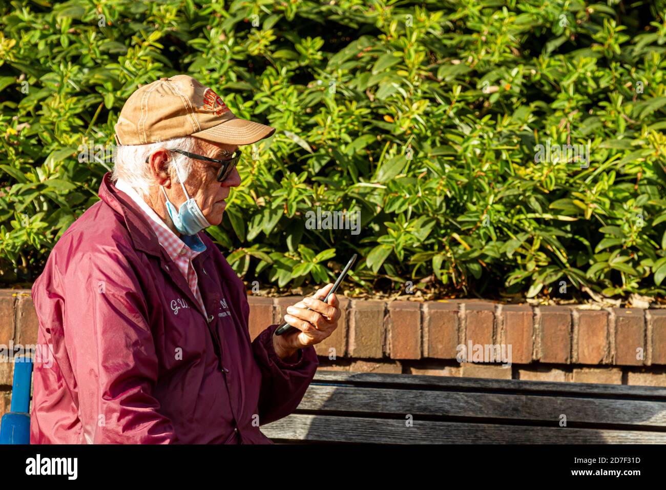 Frederick, MD, USA 10/14/2020: Ein älterer Kaukasusmann mit Gesichtsmaske versucht herauszufinden, wie man ein altes Flip-Phone benutzt, das er in han hält Stockfoto
