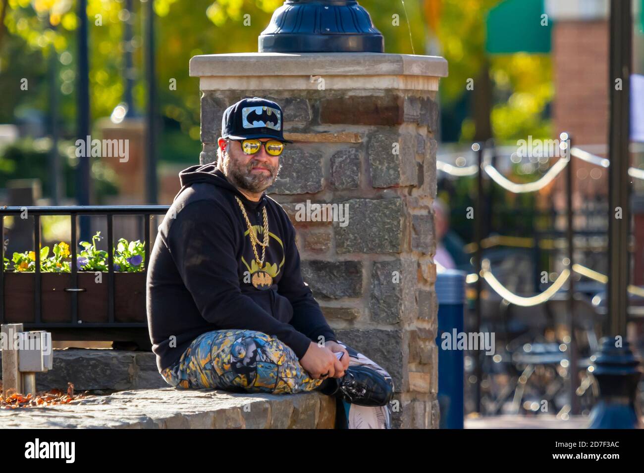 Frederick, MD, USA 10/14/2020: Ein bärtiger Kaukasianer im mittleren Alter sitzt an einer Wand an der Straße. Er ist verkleidet mit batman-Filmcharakter es Stockfoto