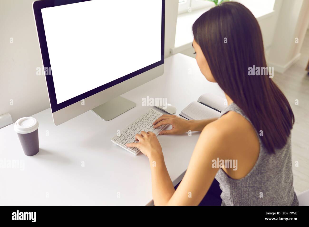 Asiatische Frau arbeitet am Computer mit leeren weißen Bildschirm sitzen Am Schreibtisch im Büro Stockfoto