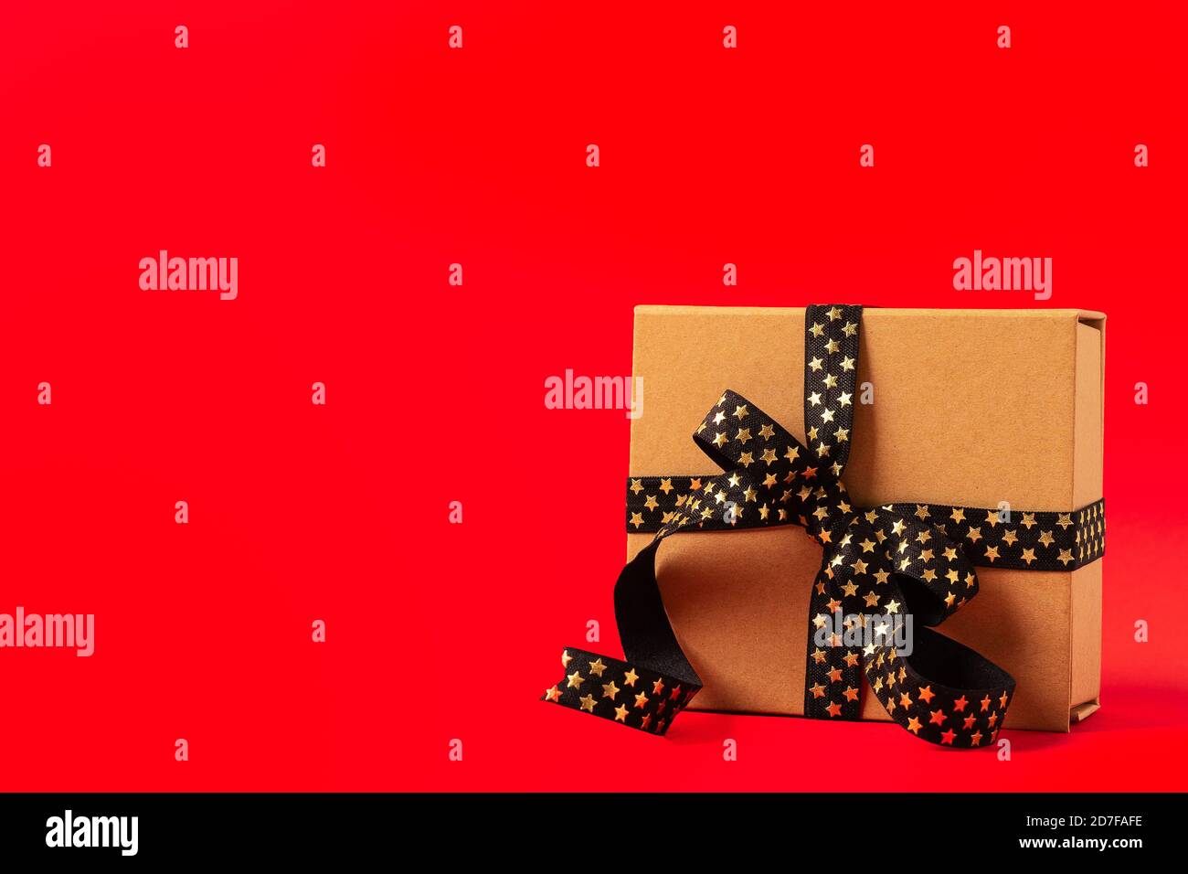Geschenkbox oder Geschenkbox mit schwarz goldenem Band auf rotem Hintergrund. Stockfoto
