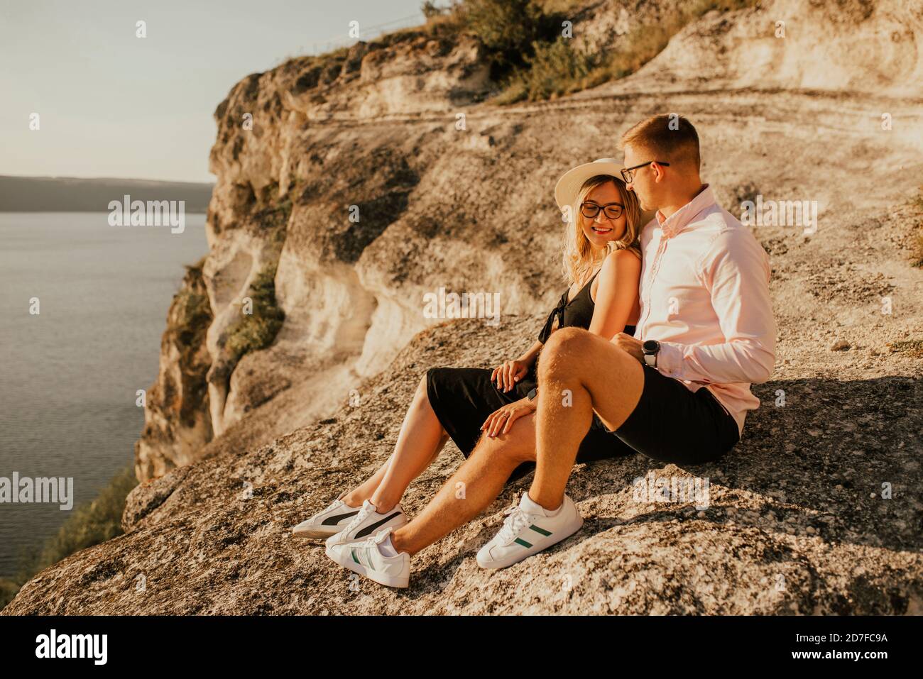 Mann und Frau im Hut sitzen auf einem großen Stein Rock Stockfoto