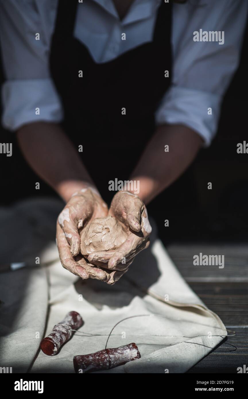 Nasse Hände bedeckt mit grauem Ton des Töpfers, der roh hält Stück Ton Stockfoto