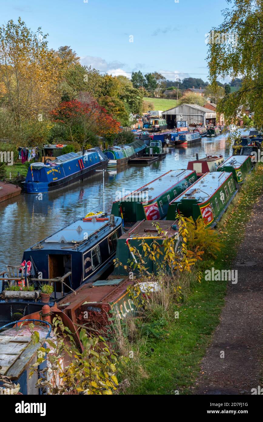 Eine Reihe von Kanalkähne und schmale Boote auf dem Grand Union Kanal in Braunston in northamptonshire und die Wartung Boot Schuppen im Herbst. Stockfoto