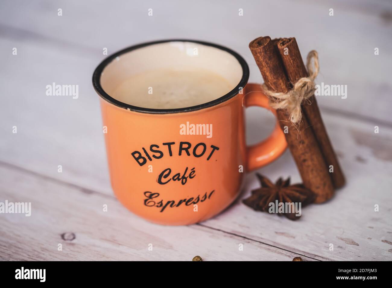 Vintage orange Kaffeetasse mit Zimt und Sternanis auf weißem Holzhintergrund. weihnachtliche Gewürze. Stockfoto