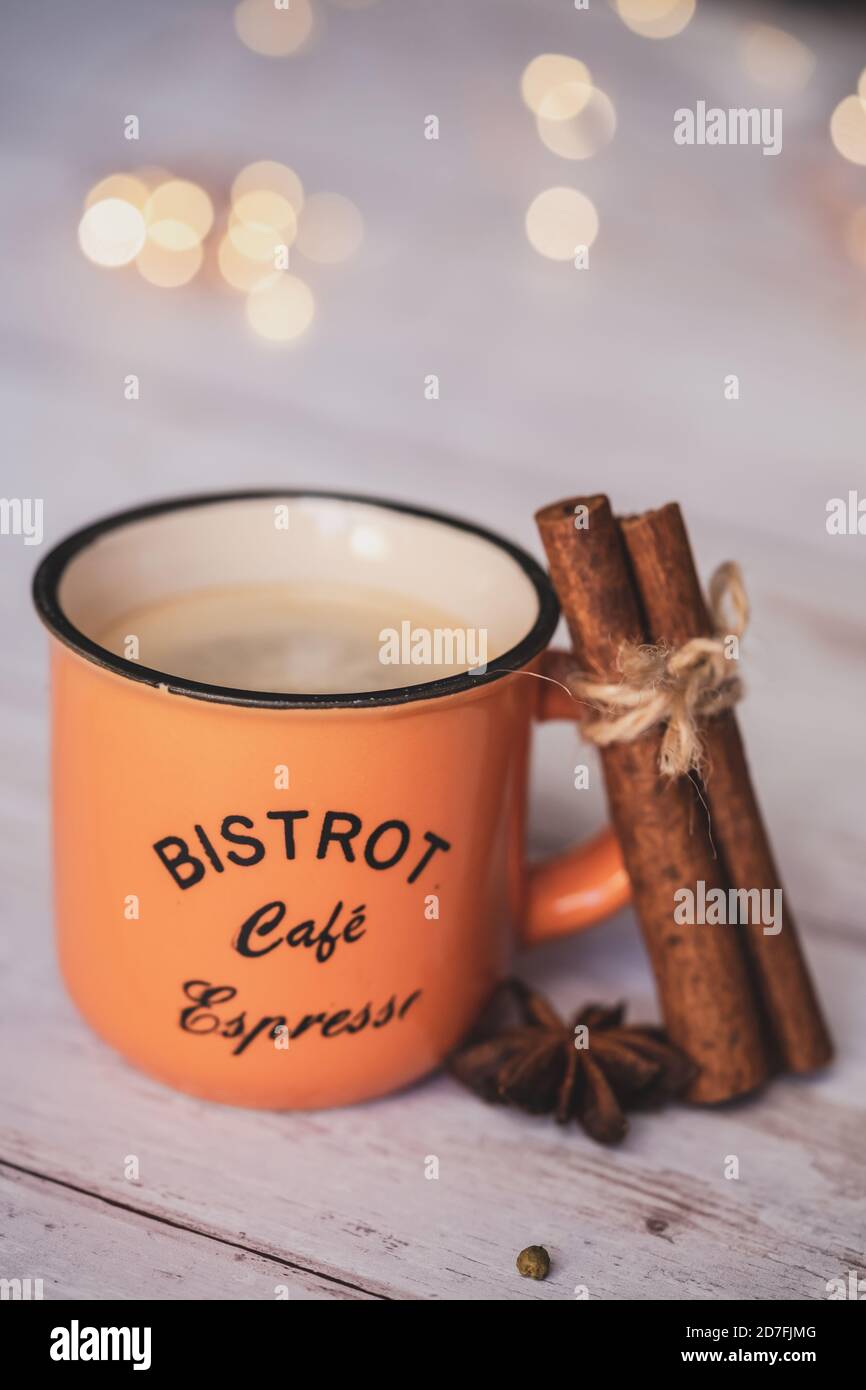Vintage orange Kaffeetasse mit Zimt und Sternanis auf weißem Holzhintergrund. weihnachtliche Gewürze. Stockfoto