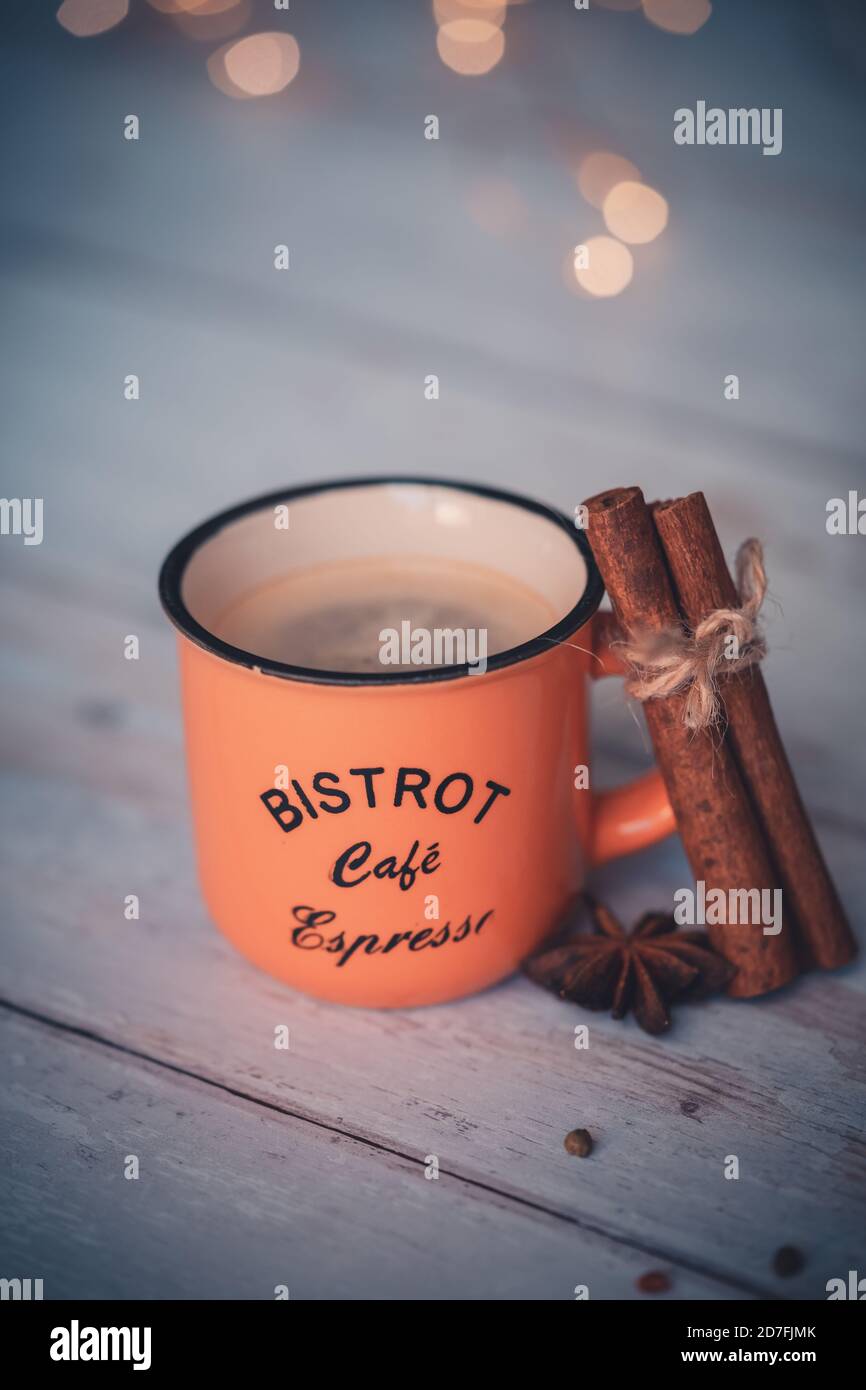 Vintage orange Kaffeetasse mit Zimt und Sternanis auf weißem Holzhintergrund. weihnachtliche Gewürze. Stockfoto