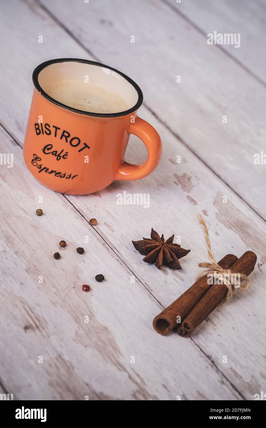 Vintage orange Kaffeetasse mit Zimt und Sternanis auf weißem Holzhintergrund. weihnachtliche Gewürze. Stockfoto