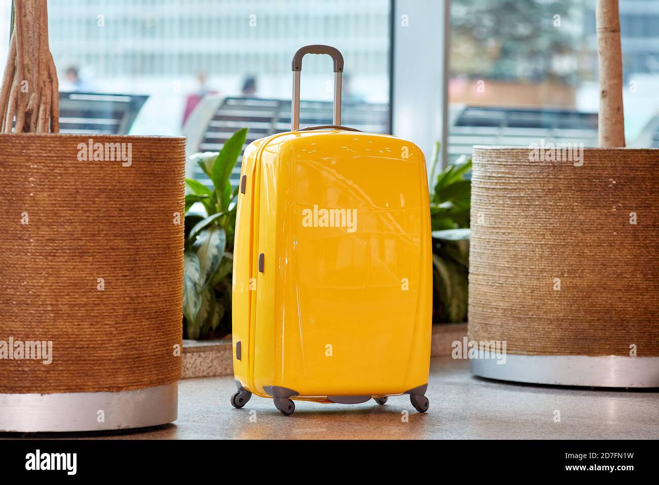 Großer gelber Koffer mit Rädern am Flughafen Stockfoto