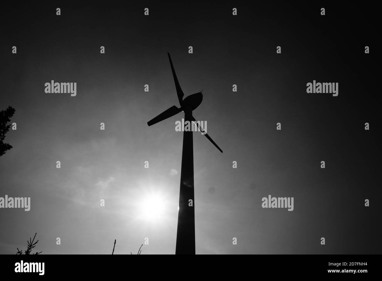 Graustufen Aufnahme einer Windmühle auf einem Hügel mit hell Sonnenlicht auf dem Hintergrund Stockfoto