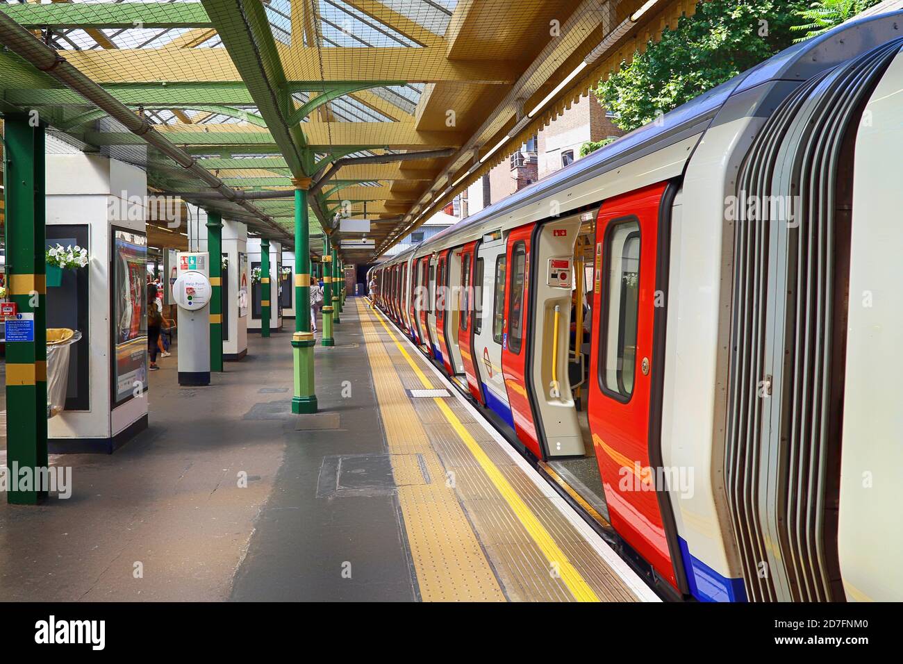 Der Bahnsteig der Londoner U-Bahn ist fast leer, eine Person in der Ferne besteigen den Zug mit allen geöffneten Türen. Die Station befindet sich auf einem Open-ai Stockfoto