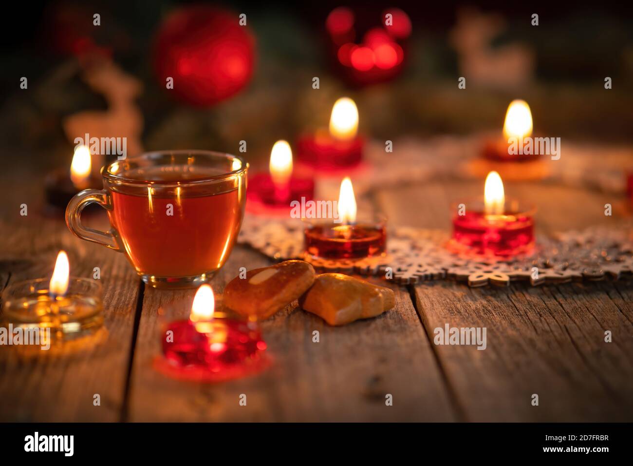 Winter-Deko mit brennenden Kerzen auf rustikalem Holztisch. Glühwein Punsch mit Lebkuchen im Vordergrund. Weihnachtsferien und Neu Stockfoto