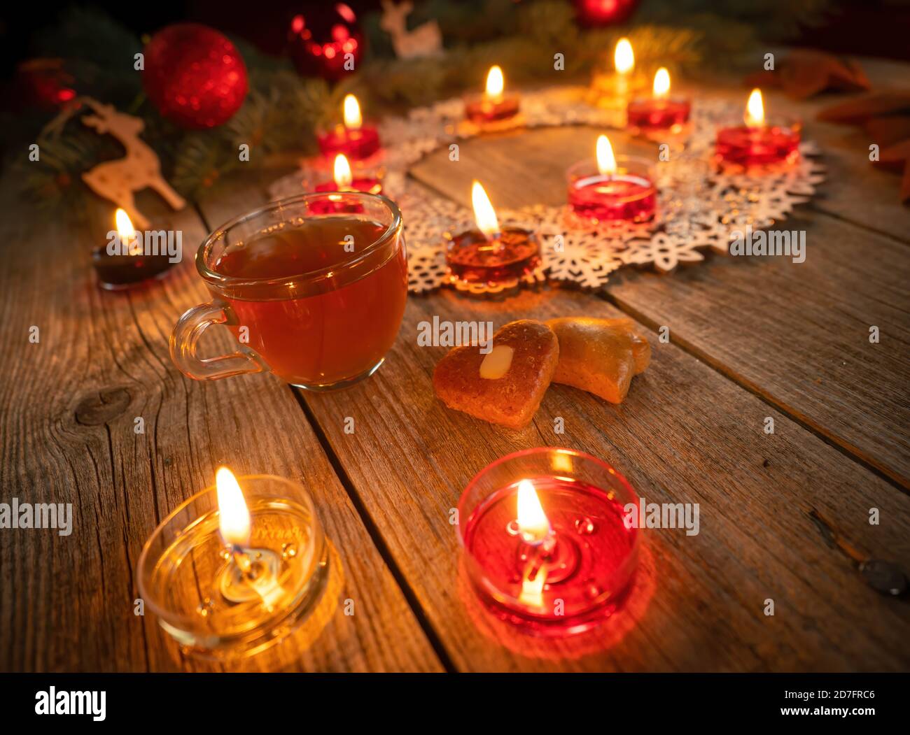 Winter-Deko mit brennenden Kerzen auf rustikalem Holztisch. Glühwein Punsch mit Lebkuchen im Vordergrund. Weihnachtsferien und Neu Stockfoto