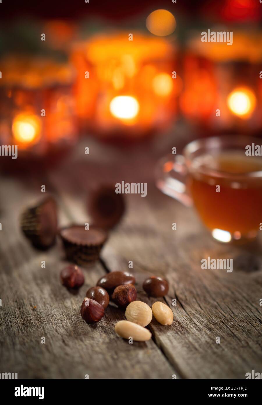 Nüsse, Süßigkeiten und hausgemachte Weihnachten Glühwein Punsch auf Holz rustikalen Tisch. Brennende Kerzen im Hintergrund. Traditionelle Herbst- und Winterheims-Szene. Stockfoto