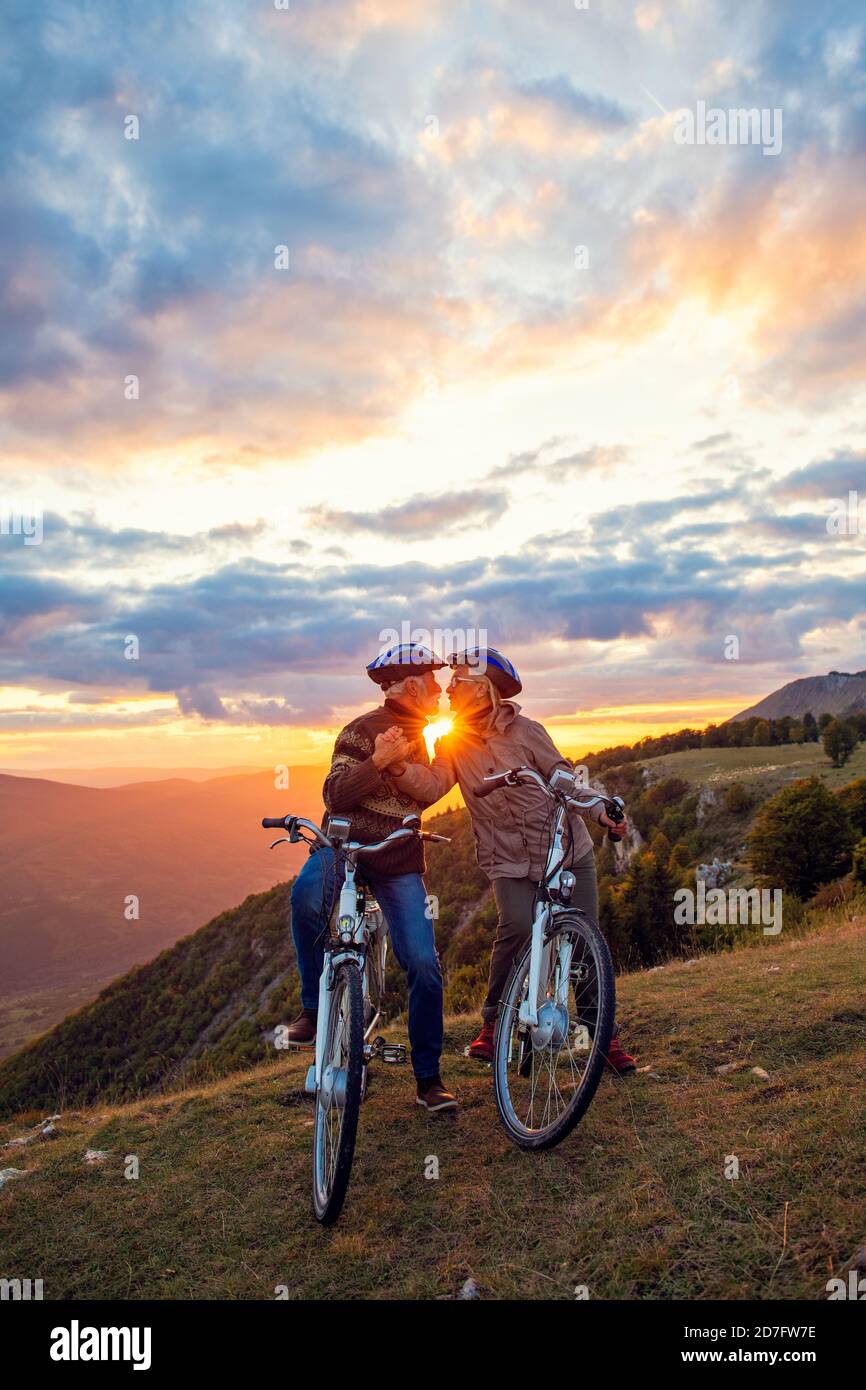 Ältere Paar mit Fahrrädern stehen am Bergpark küssen Stockfoto