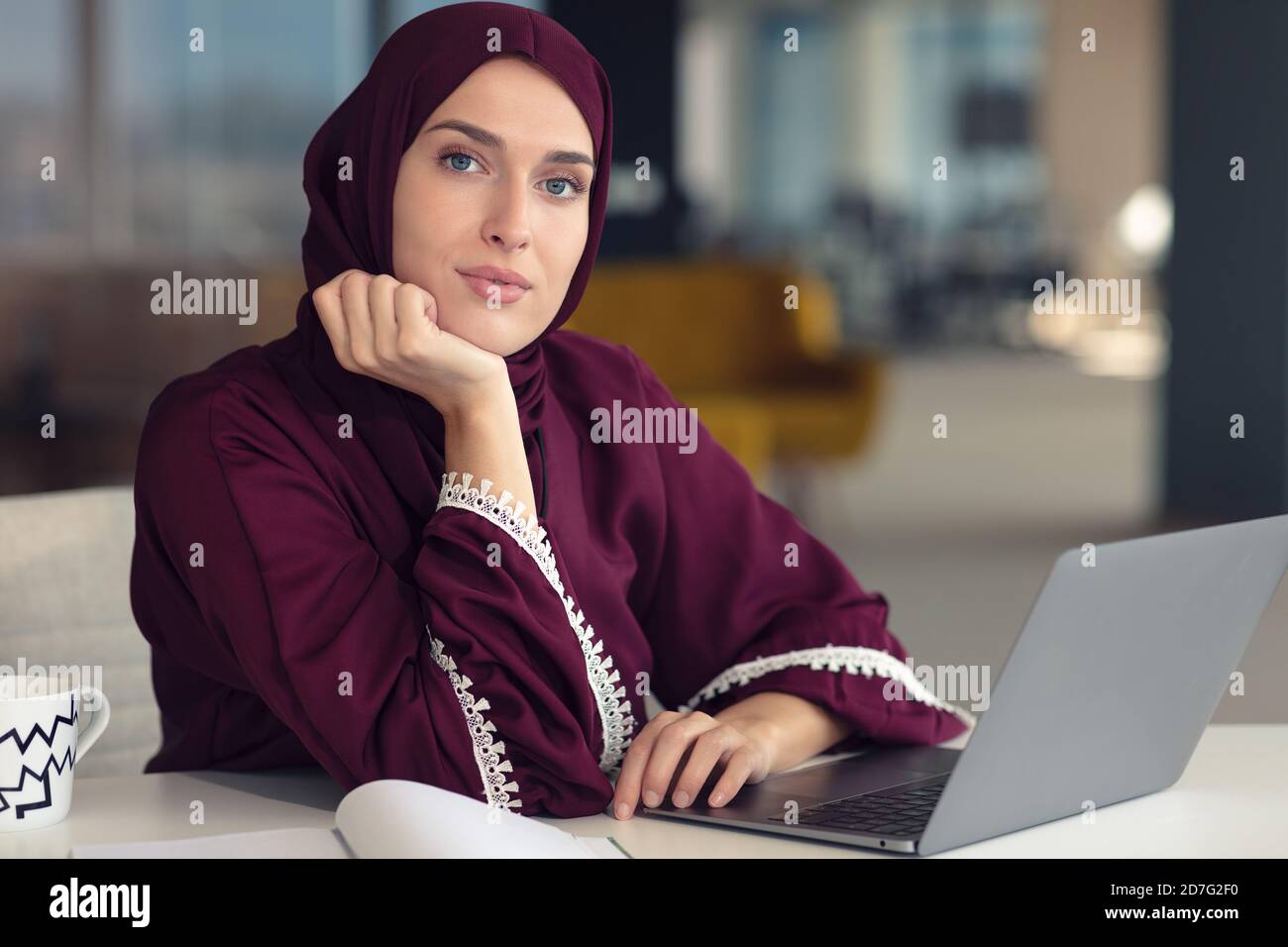 Nachdenkliche arabische Geschäftsfrau, die am Arbeitsplatz im Büro sitzt Stockfoto