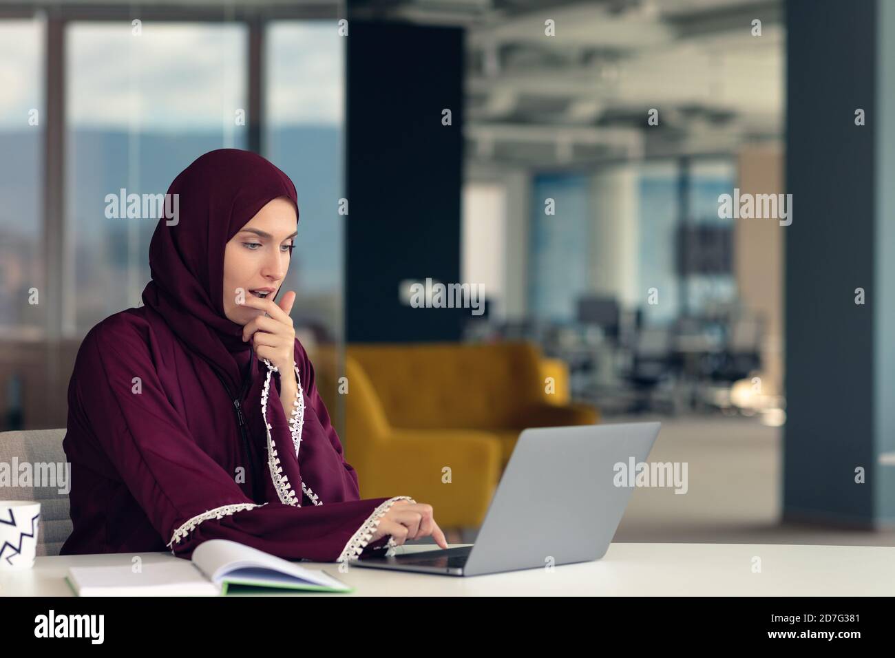 Nachdenkliche arabische Geschäftsfrau, die am Arbeitsplatz im Büro sitzt Stockfoto