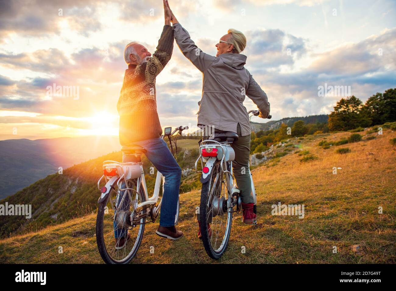 Aktives Seniorenpaar feiert Erfolg bei schönem Sonnenuntergang. Stockfoto