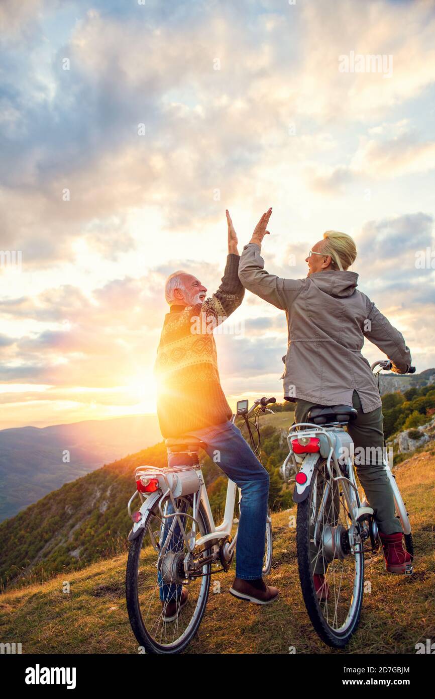 Aktives Seniorenpaar feiert Erfolg bei schönem Sonnenuntergang. Stockfoto