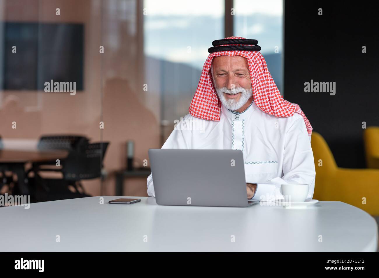 Arabischer Geschäftsmann zuversichtlich und lächelnd im Büro mit Laptop. Stockfoto