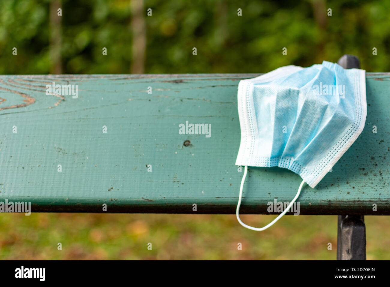 Gesundheit und Schutz von COVID-19 Konzept, EIN Stück blaue OP-Maske hängen auf einer Parkbank nach Gebrauch, Abfallbehandlung oder medizinische Maske. Stockfoto