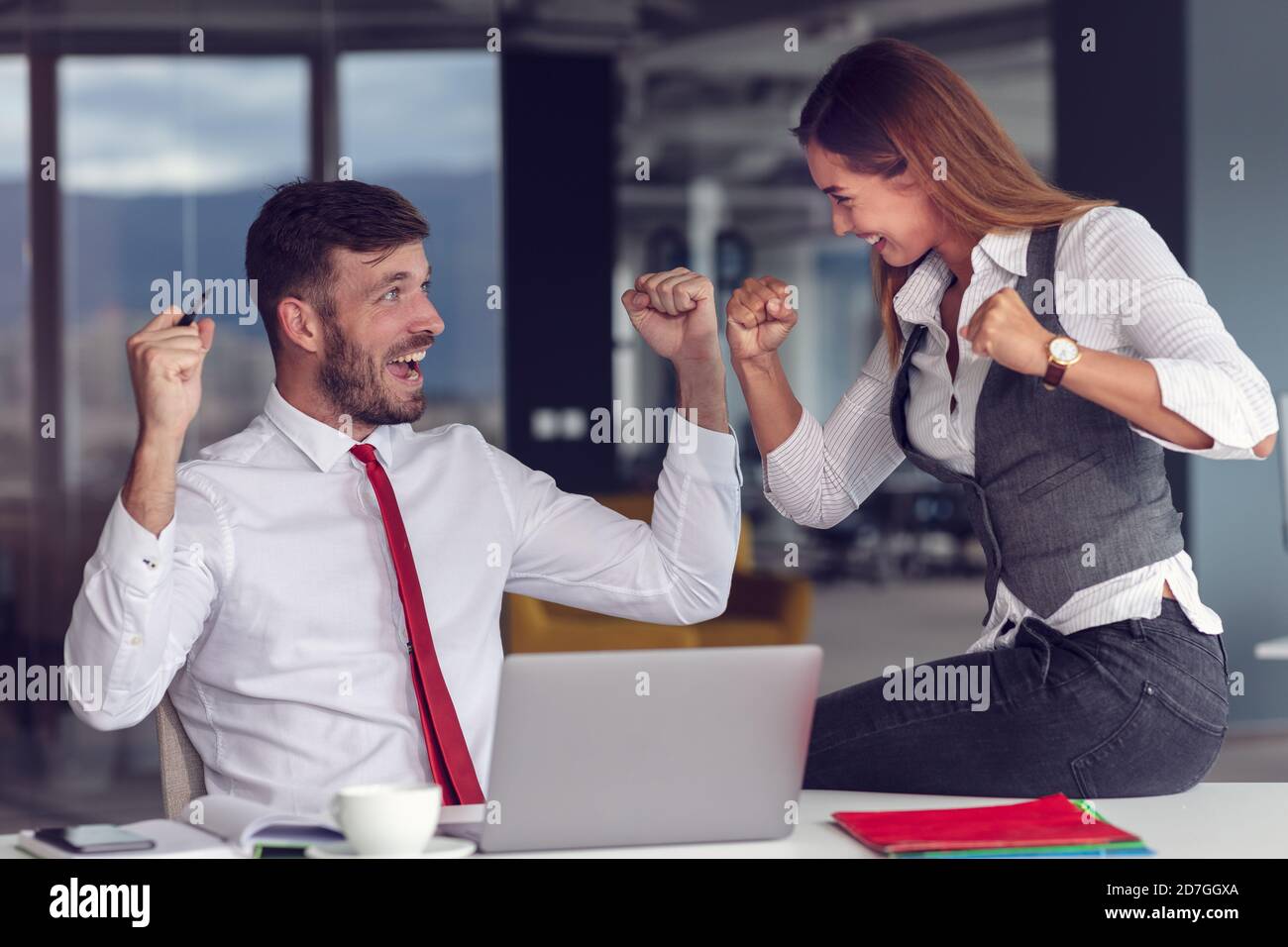 Kollegen feiern Erfolg im modernen Büro mit Laptop-Computer Stockfoto