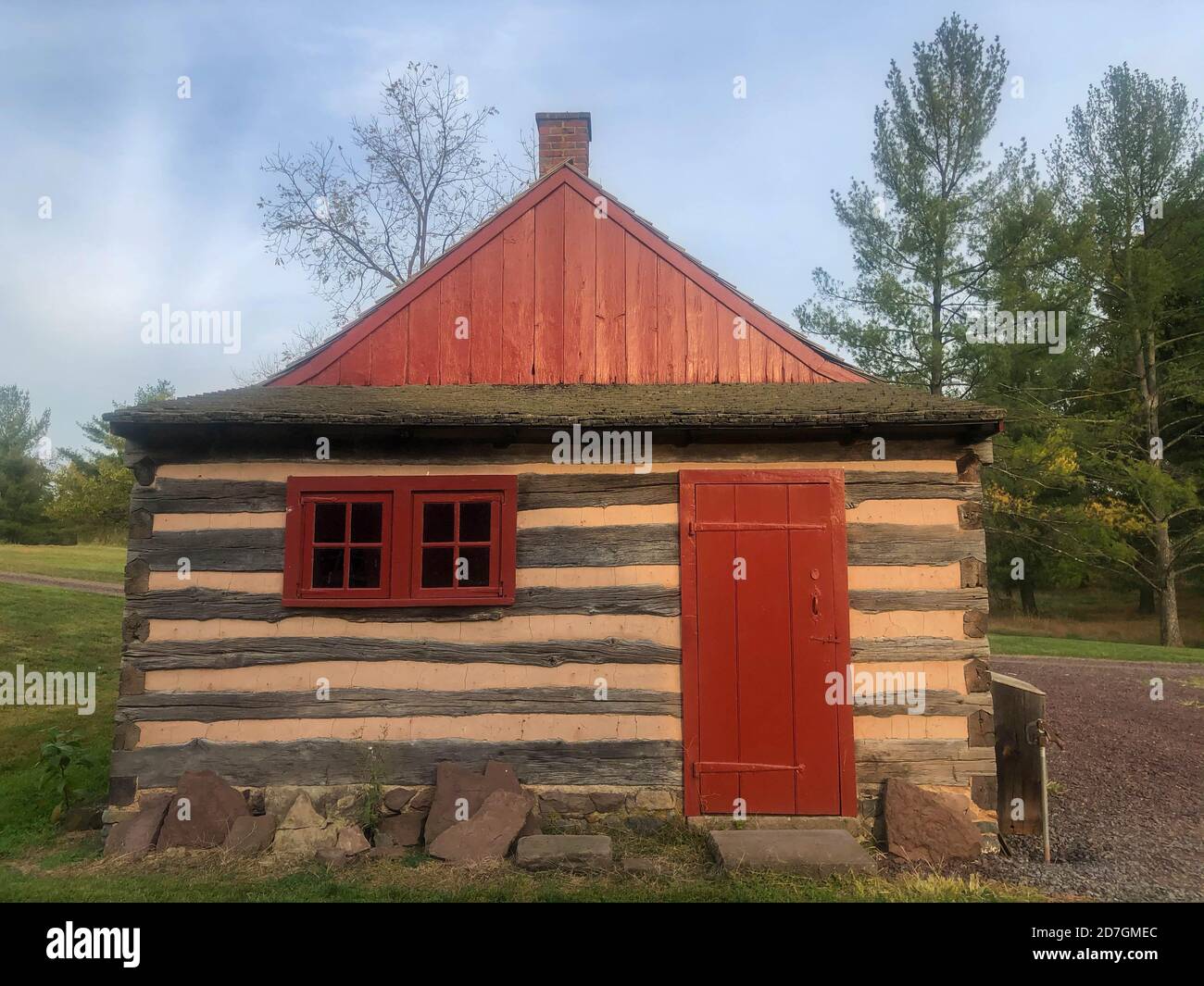 Colonial Pennsylvania Blockhütte mit roter Tür in natürlicher Umgebung. Stockfoto