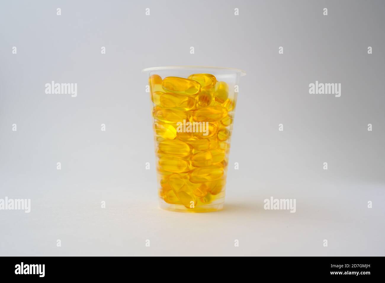 Gesundes Ernährungskonzept ein Plastikbecher mit gelbem Fisch Öl omega3 Weichmacher auf weißem Hintergrund mit Kopierraum Stockfoto