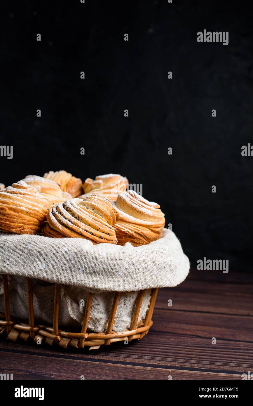Modernes Gebäck in 2020-Cruffins, eine Mischung aus Croissants und Muffins. Auf einem dunklen Tisch, bestreut mit Puderzucker. Der Blick von oben. In einem Stockfoto