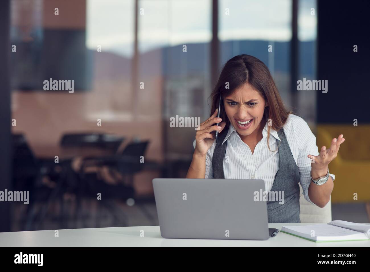 Verärgerte Geschäftsfrau am Telefon im modernen Büro Stockfoto