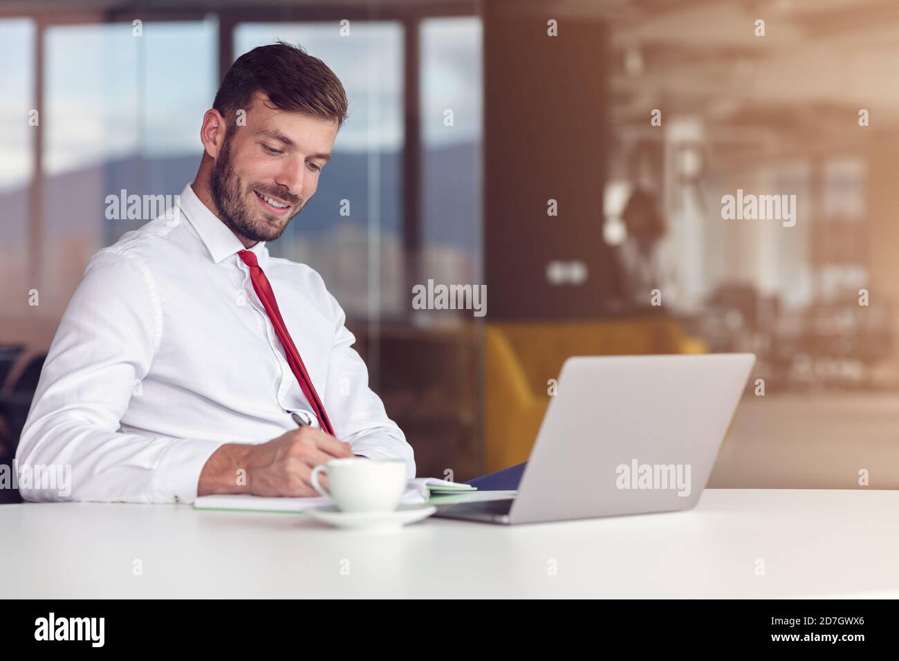Zwangloser Tag Im Büro. Lächelnder Männlicher Mitarbeiter Mit Laptop Und Kaffee Trinken. Stockfoto
