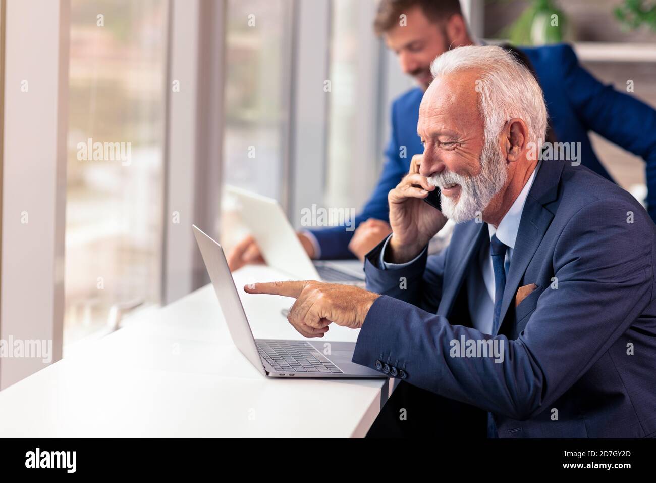 Senior Manager mit einem Handy mit jungen Kollegen in Hintergrund Stockfoto