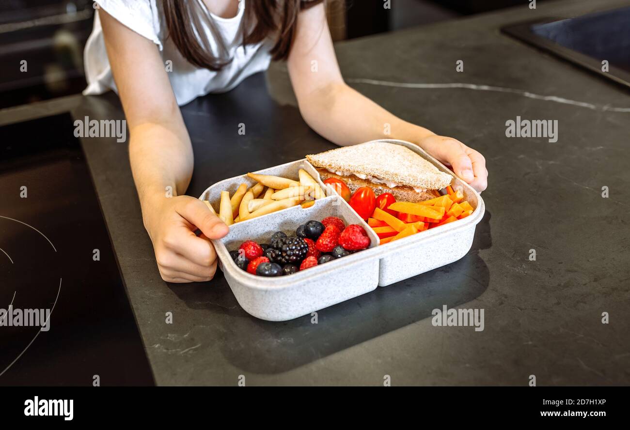 Unkenntlich Mädchen, die Lunchbox mit gesunden Lebensmitteln gefüllt Stockfoto