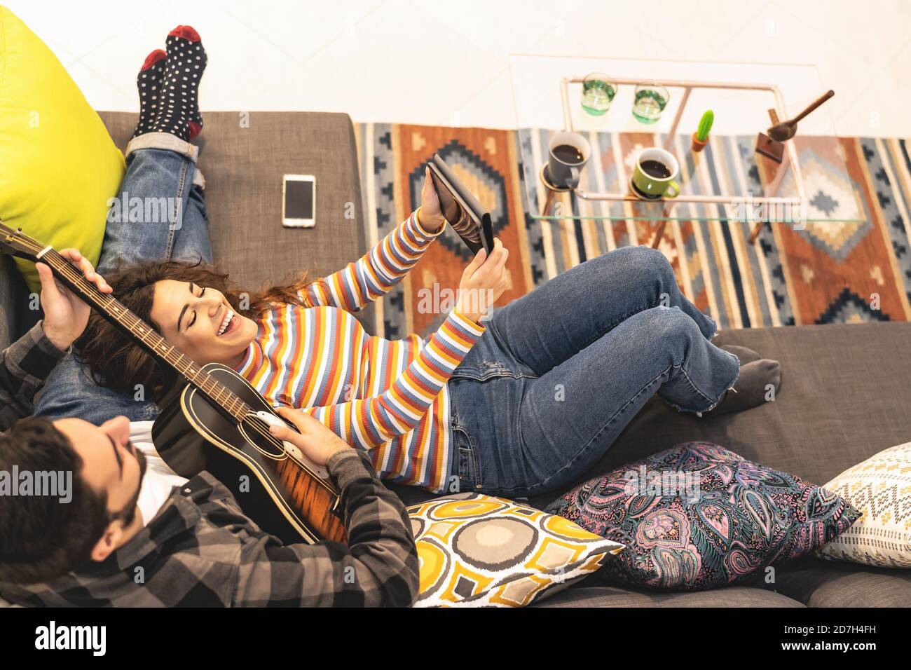Happy couple Aufnahme Video mit mobilen Tablet beim Spielen Gitarre Zu Hause - Junge romantische Liebhaber Spaß mit neuen Trends Technologie-Geräte Stockfoto