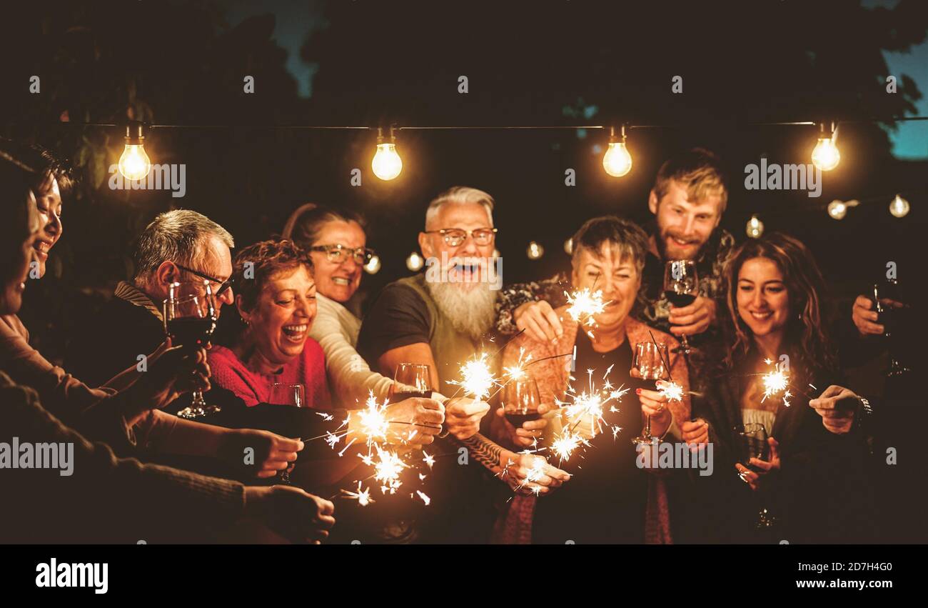 Glückliche Familie feiert mit Wunderkerzen Feuerwerk bei Nacht Party - Gruppe von Menschen mit unterschiedlichen Alters und Ethnizität Spaß haben Gemeinsam Stockfoto