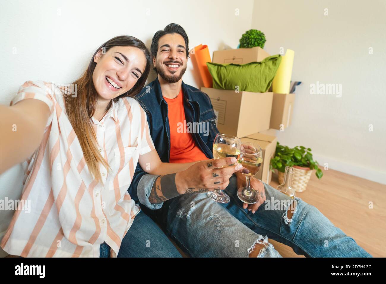 Glückliches junges Paar, das Selfie macht, während es mit Champagner feiert Neues Zuhause beim ersten Mal Stockfoto