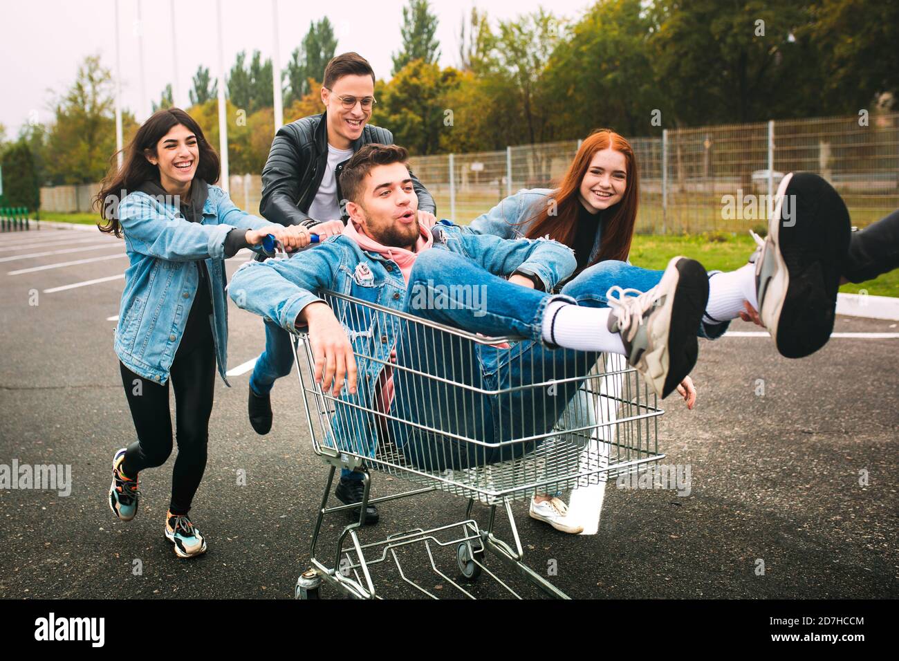 Reiten. Eine Gruppe von vier jungen, vielfältigen Freunden im Jeanse-Outfit sieht sorglos, jung und glücklich aus, wenn sie die Straßen der Stadt entlang geht. Mode der städtischen Kleidung, Freiheit, Freundschaft, Stil Konzept. Stockfoto