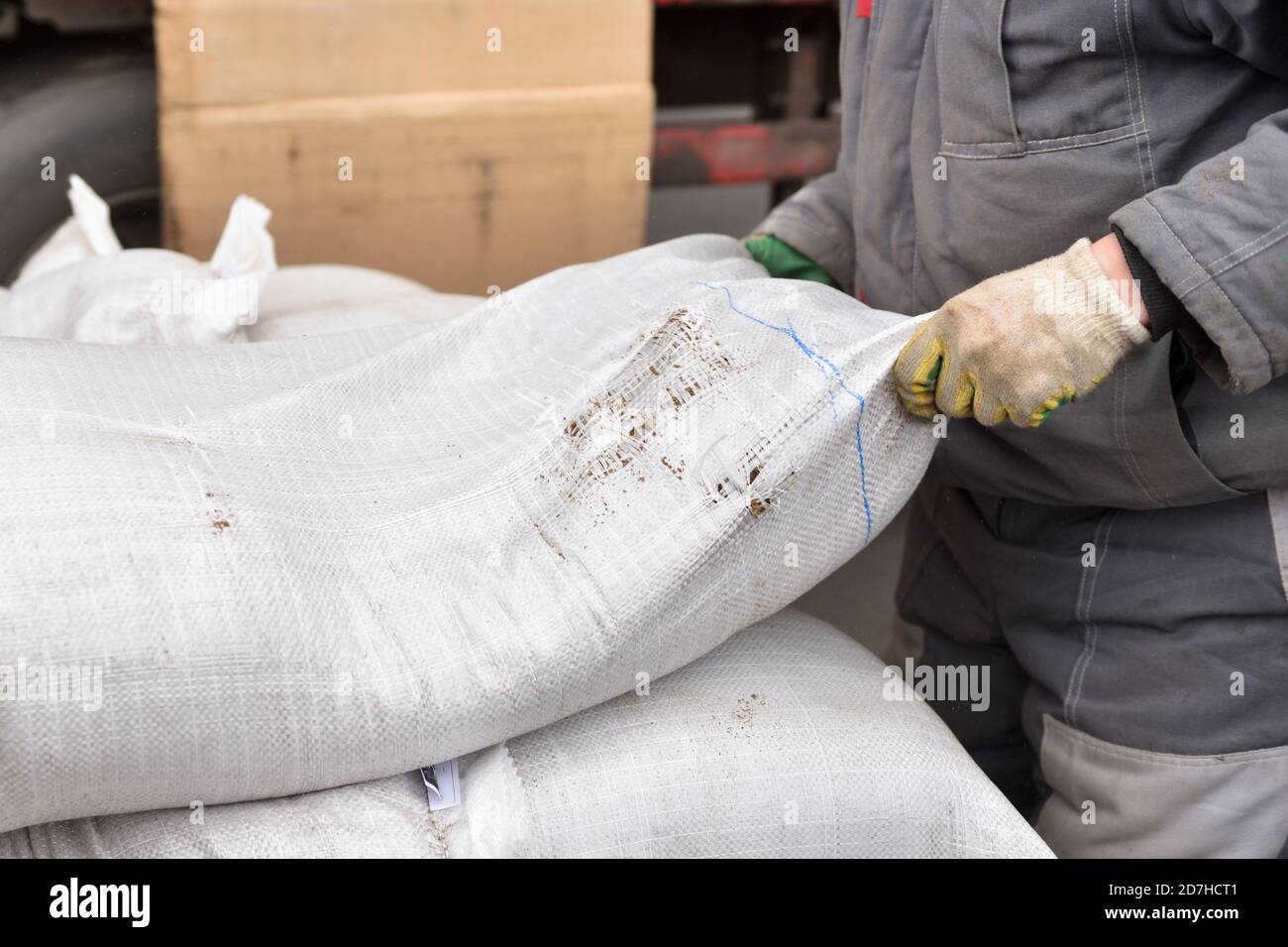 Ein Mann Lader in einer Fabrik wirft einen schweren Beutel Mit den Händen Stockfoto