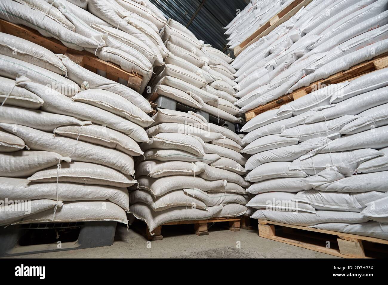 Viele weiße volle Säcke mit Getreide liegen auf Paletten hinein Ein Lager Stockfoto