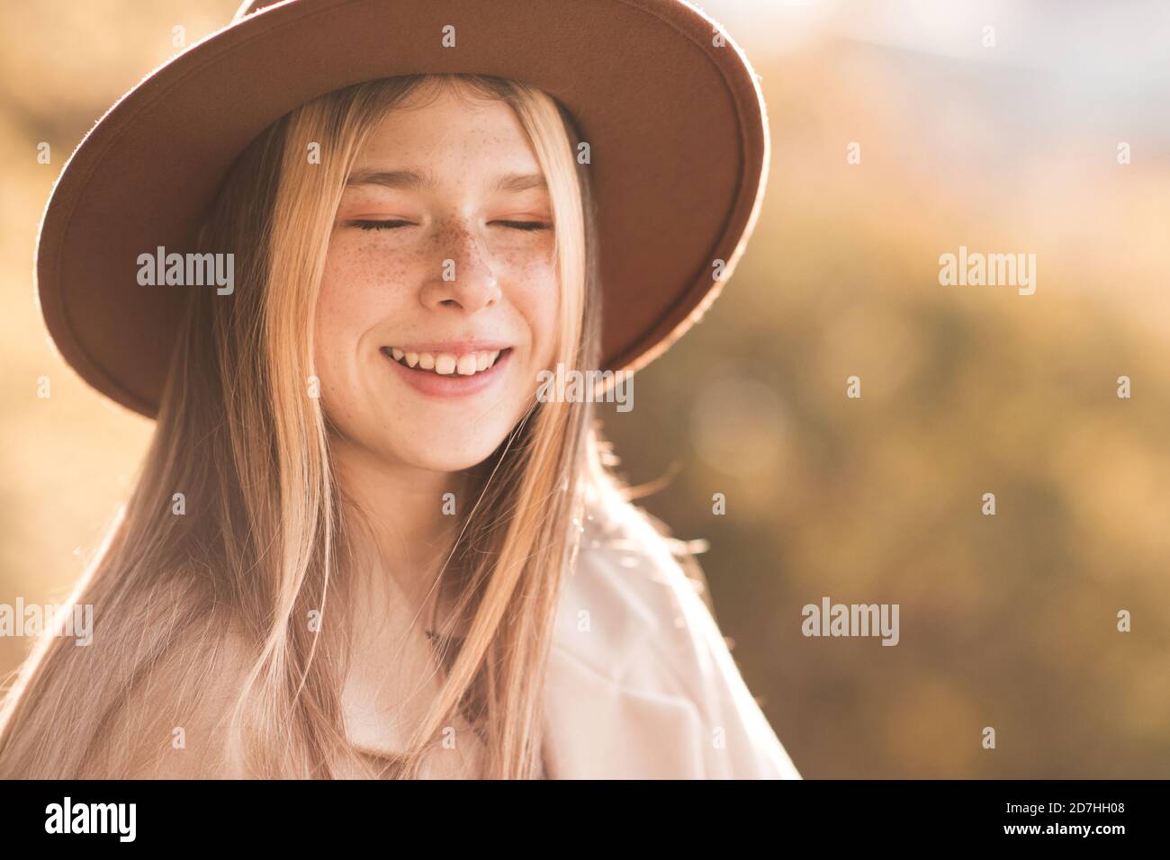 Lachen glücklich Teenager-Mädchen 13-14 Jahre alt mit geschlossenen Augen tragen stilvolle Hut und Mantel über Natur Herbst Hintergrund Nahaufnahme. Glück. Teenagerho Stockfoto