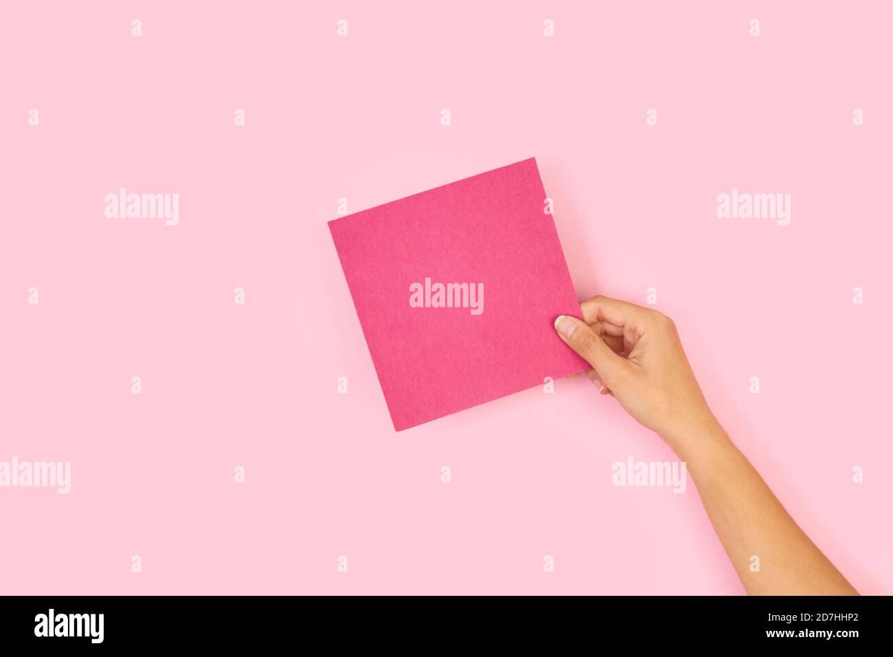 Frau Hand hält ein leeres rosa Papier auf einem rosa Hintergrund Stockfoto